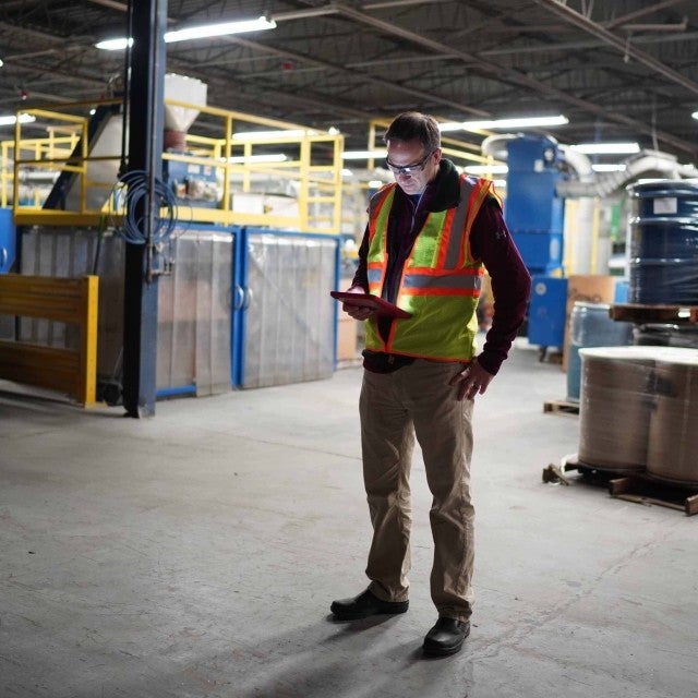 Person standing in warehouse looking at tablet 