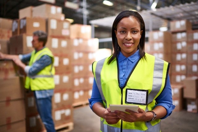 Team member in safety vest with tablet in warehouse 