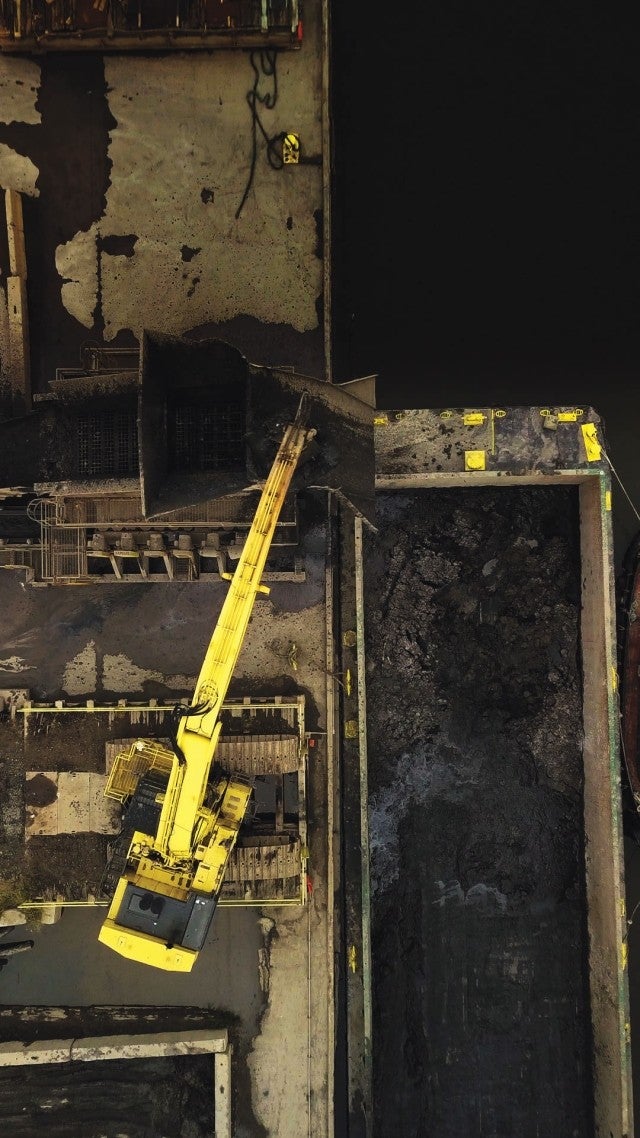 Excavator moving material from barge 